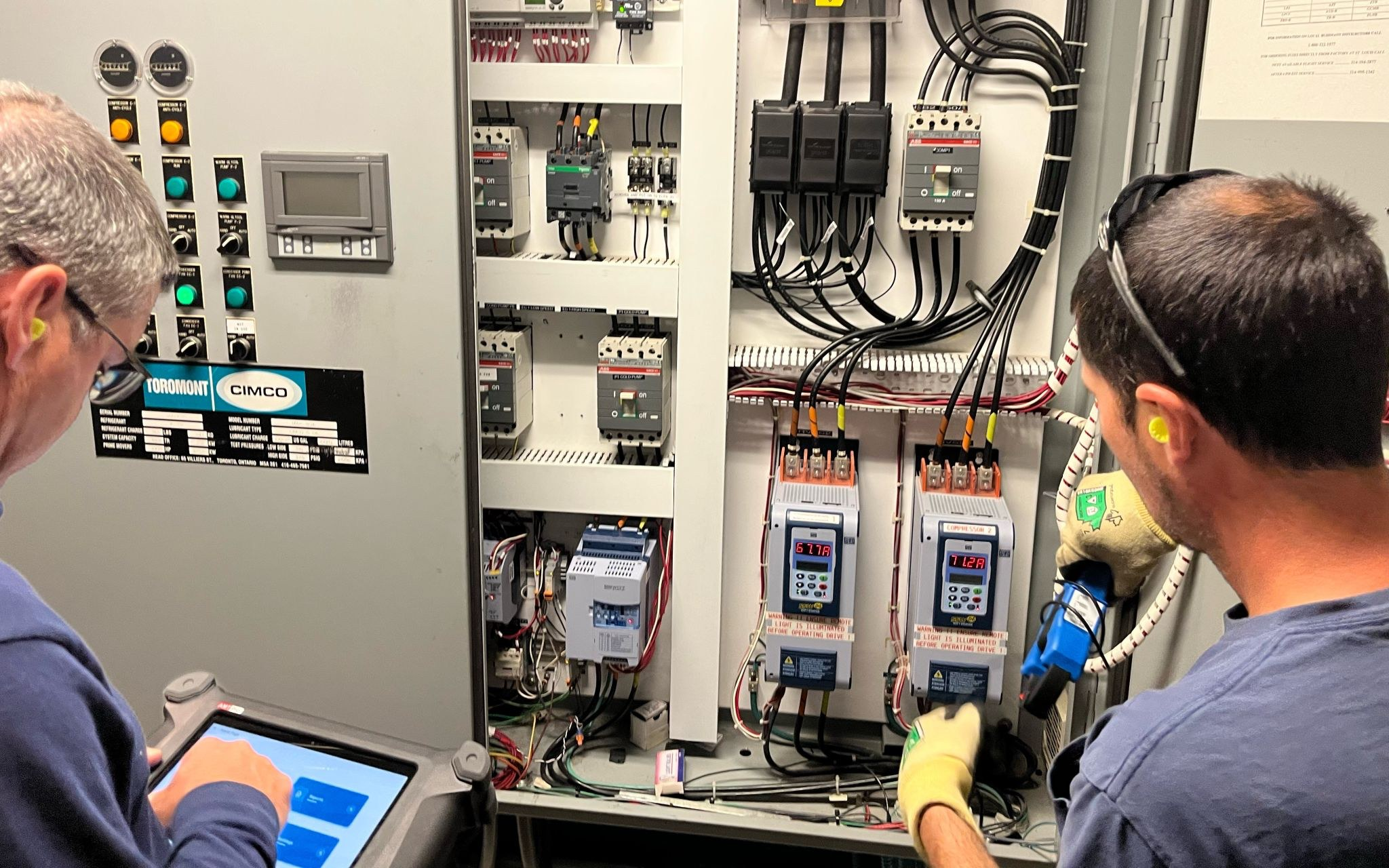 AMTPro - Test 1 Two engineers running an AMTPro test at a compressor control panel: one on the AMTPro tablet, one connecting at the drive