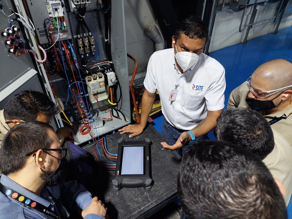 Home Test 8 A team reviewing portable testing equipment beside an open electrical cabinet